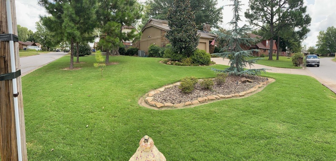 A landscaped Tulsa front yard with shaped mulch beds and a healthy green lawn